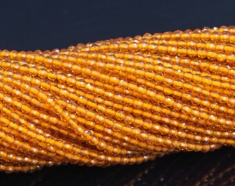 May include: A strand of orange faceted glass beads. The beads are small and round, and they have a shiny, polished finish.