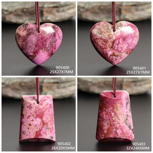 May include: Four pink gemstone pendants with varying shapes. Two are heart-shaped, and two are rectangular. Each pendant is attached to a maroon cord. The pendants have a marbled appearance with pink and brown hues. The dimensions are listed on each pendant.