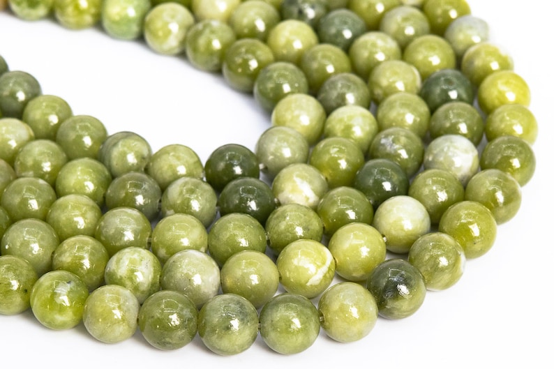 May include: A strand of round, green jade beads. The beads are smooth and polished, with a slight variation in colour.