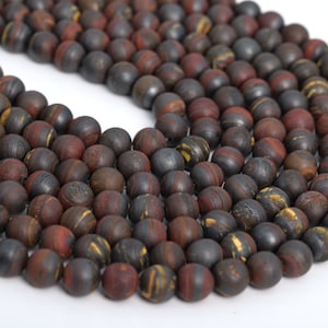 May include: A strand of dark brown, red, and gold striped round beads. The beads are made of natural stone and have a matte finish.