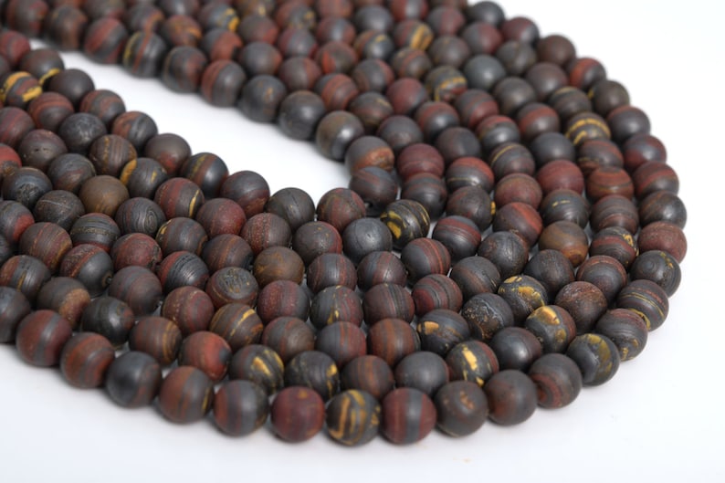 May include: A strand of dark brown, red, and gold striped round beads. The beads are made of natural stone and have a matte finish.