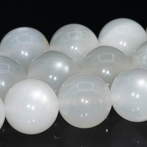 May include: A strand of white moonstone beads. The beads are round and smooth, with a pearly sheen.