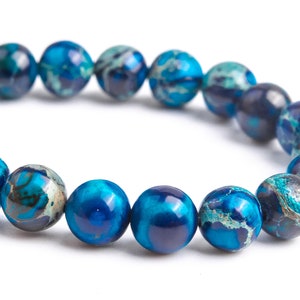 K&ouml;nnte beinhalten: Ein blaues und wei&szlig; gemustertes Perlenarmband. Die Perlen sind rund und haben eine marmorierte Optik.