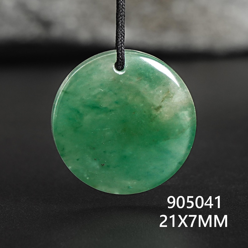 Pu&ograve; includere: Un ciondolo rotondo di giada verde lucidata con un cordino nero. Il ciondolo misura 2,1 cm di diametro e 0,7 cm di spessore. L'immagine include anche i numeri "905041".