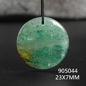 Pu&ograve; includere: Un ciondolo rotondo verde con un cordino nero. Il ciondolo misura 23 mm di diametro e 7 mm di spessore. La pietra presenta una miscela di tonalit&agrave; verdi e gialle con un aspetto marmorizzato. Il testo "905044" &egrave; sotto.