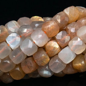 May include: A strand of faceted sunstone beads in shades of peach, orange, and white. The beads have a shimmery, iridescent finish.