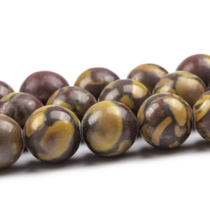 May include: A strand of brown and yellow marbled round beads. The beads have a mottled pattern of brown and yellow.