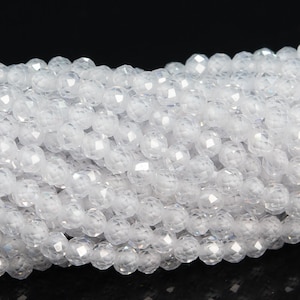 May include: A strand of white faceted gemstone beads. The beads are round and have a smooth, polished finish.