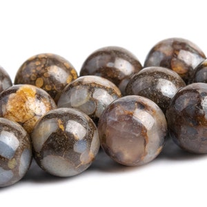 May include: A strand of brown and white agate beads with a speckled pattern. The beads are round and smooth.