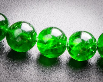 Puede incluir: Primer plano de un collar de cuentas de vidrio verde vibrante. Las cuentas son perfectamente redondas y tienen una superficie brillante y reflectante. Las cuentas están ensartadas, creando un hermoso accesorio. Las cuentas tienen aproximadamente 2 cm de diámetro.