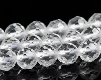 Puede incluir: Primer plano de una hebra de cuentas de cristal facetadas transparentes. Las cuentas son redondas y tienen un acabado liso y pulido.
