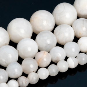 May include: A strand of white moonstone beads, each bead is round and smooth. The beads are arranged in a graduated size, with the largest beads at the top and the smallest beads at the bottom.