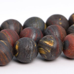 May include: A strand of round, dark brown, red, and gold gemstone beads. The beads have a swirling, marbled pattern.