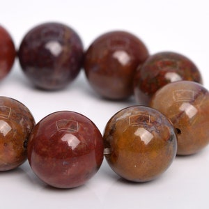 May include: A strand of brown, red, and white gemstone beads. The beads are round and have a smooth, polished finish.