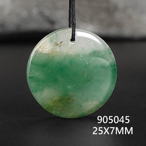 Pu&ograve; includere: Ciondolo rotondo in giada verde e bianca, con cordino nero. La pietra lucida misura 25 mm x 7 mm. Il ciondolo ha un aspetto naturale e traslucido.