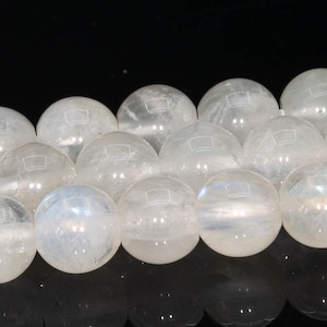 May include: A strand of white moonstone beads, each bead is a smooth, round sphere with a slight iridescent shimmer.