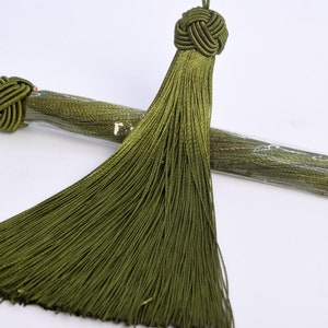 May include: Two green silk tassels with knotted tops. The tassels are wrapped in clear plastic and are ready to be used for crafts or embellishments.