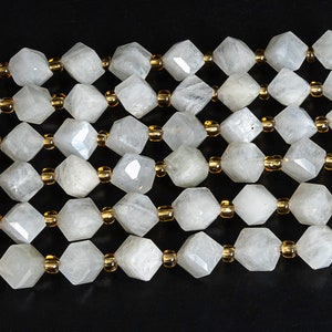May include: A strand of white gemstone beads with a faceted, hexagonal shape. The beads are interspersed with smaller, gold-colored beads.
