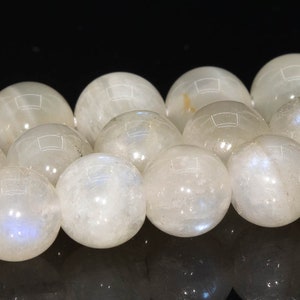 May include: A strand of white moonstone beads. The beads are round and smooth, with a slight iridescent sheen.