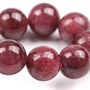 May include: A bracelet made of round, dark red gemstone beads.