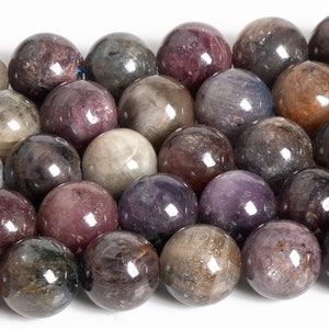 May include: A strand of round, smooth, gemstone beads in shades of gray, purple, and brown. The beads have a slightly iridescent sheen.