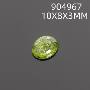 May include: A translucent, oval-shaped gemstone with a vibrant green hue. The gem measures approximately 0.4 x 0.3 x 0.1 inches and features inclusions within its structure. The text "904967 10X8X3MM" is displayed above the gem.
