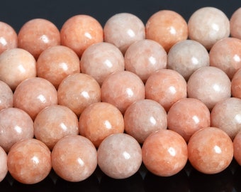 May include: A strand of smooth, round, peach-colored beads. The beads are made of natural stone and have a polished finish.