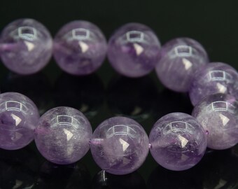 May include: A close-up of a strand of amethyst beads. The beads are round, approximately 10mm in diameter, and a translucent purple color. The beads have a polished surface and are strung together on a purple string.