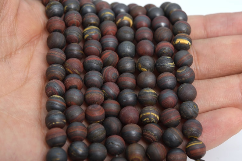 May include: A strand of round, dark brown, red, and gold striped beads. The beads are made of natural stone and have a smooth, polished finish.