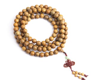 May include: A brown wooden beaded necklace with a red tassel and a green jade charm. The necklace is coiled in a circle on a white background.