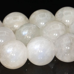 May include: A strand of white moonstone beads, each bead is a smooth sphere with a subtle iridescent sheen.