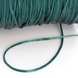 May include: A spool of dark green twine with a length of twine extending from the spool.