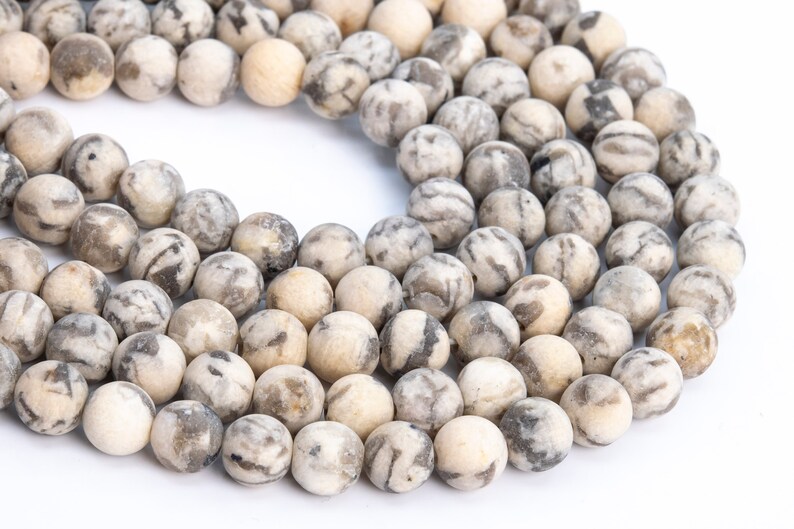 May include: A strand of round, white and gray agate beads. The beads have a marbled pattern and are approximately 8mm in diameter.
