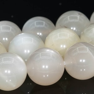 May include: A strand of white moonstone beads, each bead is round and smooth with a pearly sheen.