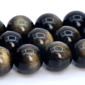 May include: A strand of black and gold gemstone beads. The beads are round and have a smooth, polished finish. The gold flecks in the beads create a shimmering effect.