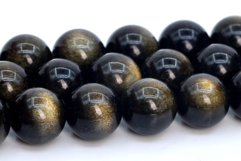 May include: A strand of black and gold gemstone beads. The beads are round and have a smooth, polished finish. The gold flecks in the beads create a shimmering effect.