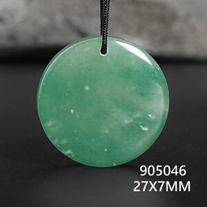 Pu&ograve; includere: Un ciondolo rotondo verde con un cordino nero. Il ciondolo misura 27 mm di diametro e 7 mm di spessore. La superficie presenta inclusioni bianche. Il testo "905046" &egrave; sotto.