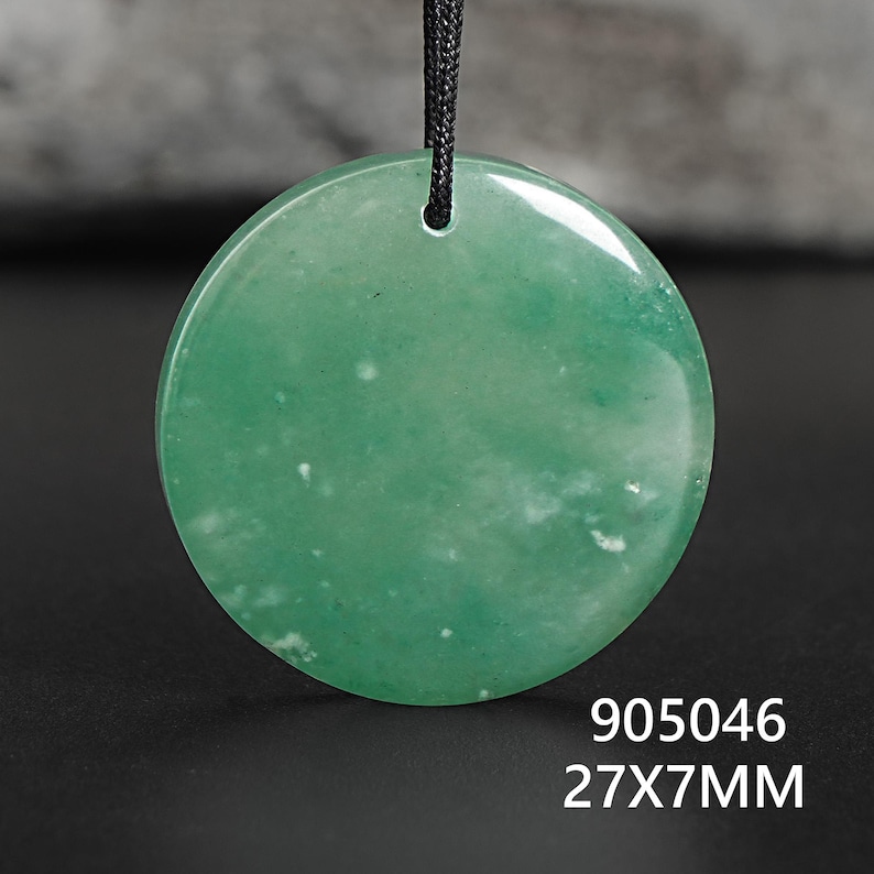 Pu&ograve; includere: Un ciondolo rotondo verde con un cordino nero. Il ciondolo misura 27 mm di diametro e 7 mm di spessore. La superficie presenta inclusioni bianche. Il testo "905046" &egrave; sotto.