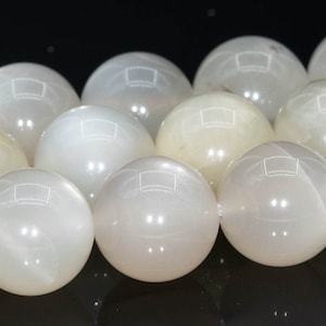 May include: A strand of white moonstone beads. The beads are round and smooth, with a pearly sheen.