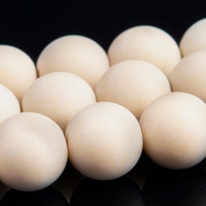 May include: A close-up of a row of smooth, off-white, round beads. The beads are arranged in a staggered pattern, creating a visual texture.