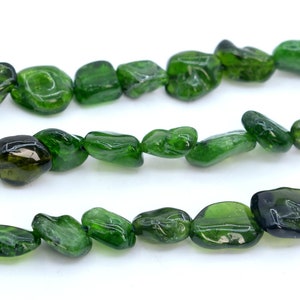 May include: A strand of green gemstone beads, each bead is a smooth, irregular oval shape.