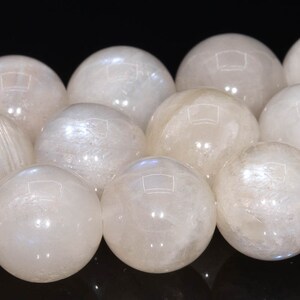 May include: A strand of white moonstone beads, each bead is a smooth sphere with a subtle iridescent sheen.