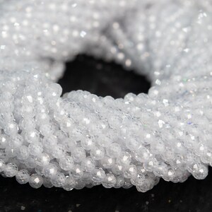 May include: A strand of white faceted crystal beads. The beads are round and have a smooth, polished finish.