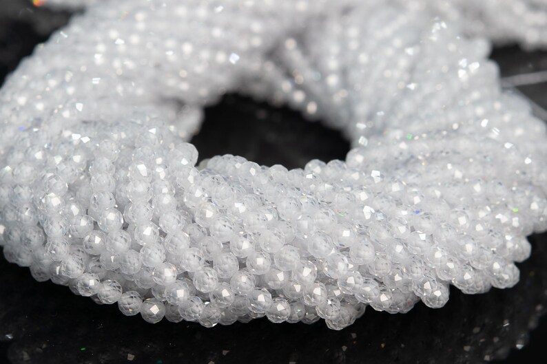 May include: A strand of white faceted crystal beads. The beads are round and have a smooth, polished finish.