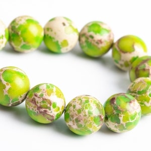 May include: A strand of green and white marbled beads. The beads are round and have a speckled pattern.