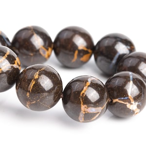 May include: A strand of dark brown gemstone beads with gold and white marbling. The beads are round and have a smooth, polished finish.