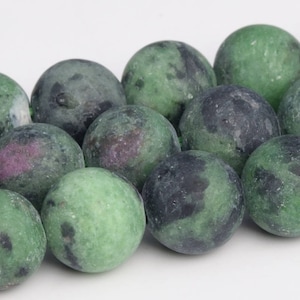 Puede incluir: Una hebra de cuentas de piedras preciosas verdes, negras y rosas. Las cuentas son redondas y tienen un aspecto moteado.