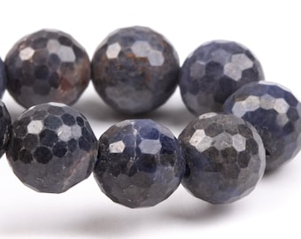 May include: A strand of dark blue faceted gemstone beads. The beads are round and have a textured surface.