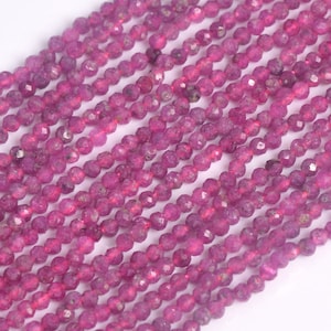 May include: Strands of faceted, round, deep magenta gemstone beads. The beads are strung together, creating multiple parallel lines of the same color. The beads have a slightly irregular shape and a subtle sparkle.