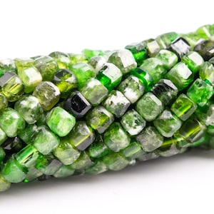 May include: A strand of green tourmaline beads, each bead is faceted and has a square shape.